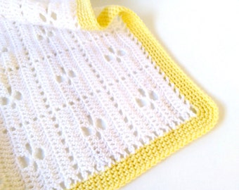 May include: A white crocheted baby blanket with a yellow crocheted border.