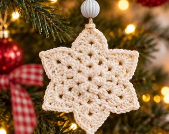May include: A cream-colored crocheted star ornament featuring a six-pointed design with intricate openwork stitching. The star hangs from a jute twine loop adorned with a small gold-toned metal bead and a ribbed light blue spherical bead.