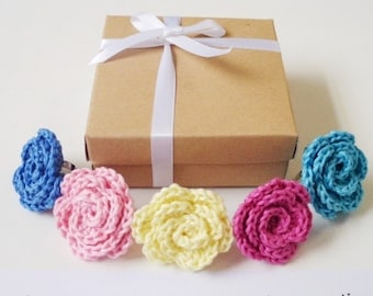 May include: Four crocheted flower rings in a gift box. The rings are in shades of blue, pink, yellow, and red.
