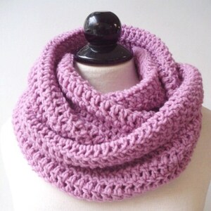 May include: A soft, purple knitted infinity scarf. The scarf is made of a chunky yarn and has a simple, textured design.