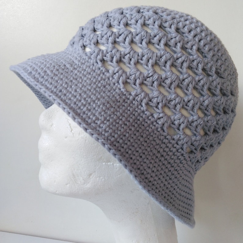 Peut inclure: Un chapeau de soleil en crochet gris avec un large bord et un motif ajour&eacute;.