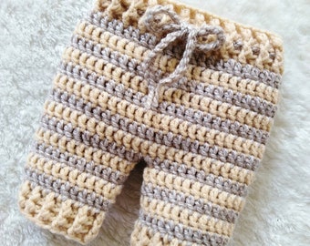May include: Crocheted baby pants in beige and gray stripes with a drawstring tie.