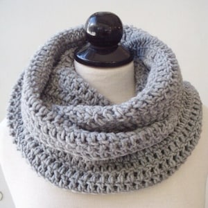 May include: A gray crocheted infinity scarf. The scarf is made with a simple stitch pattern and is thick and warm.