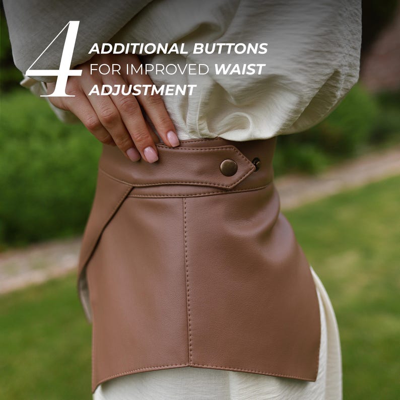 May include: A brown leather waist belt with a button closure. The belt has a unique design with a flap detail and is shown with the text "4 ADDITIONAL BUTTONS FOR IMPROVED WAIST ADJUSTMENT".