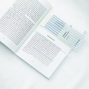 May include: A close-up of a book with a blue and white highlighter. The book is open to a page with text about design and architecture. The text on the highlighter reads "ORDINATE HIGHLIGHTER".