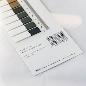 May include: A package of "Dusk Charm" Morandi Deep Half Color Tabs. The tabs are rectangular, with a white base and a colored top in shades of brown, green, and navy. A ruler is printed along the edge. The product size is 11mm x 45mm.