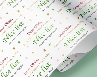 May include: White wrapping paper with a repeating pattern of green text that says "Dear Olivia, Santa Claus Has Placed You On The Nice List" with pink stars and gold stars.