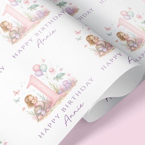 May include: White wrapping paper with a repeating pattern featuring a pink number one, a mermaid, balloons, and sea creatures. The text "HAPPY BIRTHDAY Annie" is written in a purple script.