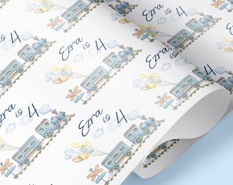 May include: White wrapping paper with a repeating pattern of blue and brown toy trains with yellow balloons. The text "Ezra is 4" is repeated throughout the pattern.