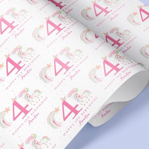 May include: White wrapping paper with a repeating pattern of pink unicorns, rainbows, stars, and the number 4. The text "Happy 1st Birthday Amelia" is repeated throughout the pattern.