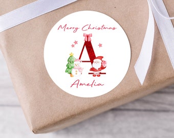 Könnte beinhalten: Runder Weihnachtsgeschenkanhänger mit einem roten Glitzerbuchstaben A, Weihnachtsmann, Schneemann und Weihnachtsbaum. Der Anhänger lautet "Frohe Weihnachten Amelia".