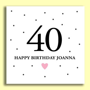 May include: A white card with black polka dots and the number 40 in black. The text "Happy Birthday Joanna" is below the number. A small pink heart is below the text.