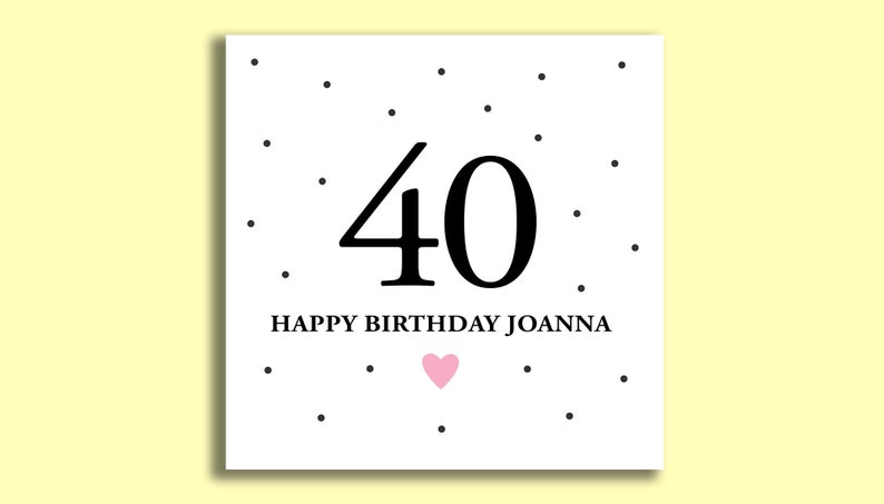 May include: A white card with black polka dots and the number 40 in black. The text "Happy Birthday Joanna" is below the number. A small pink heart is below the text.