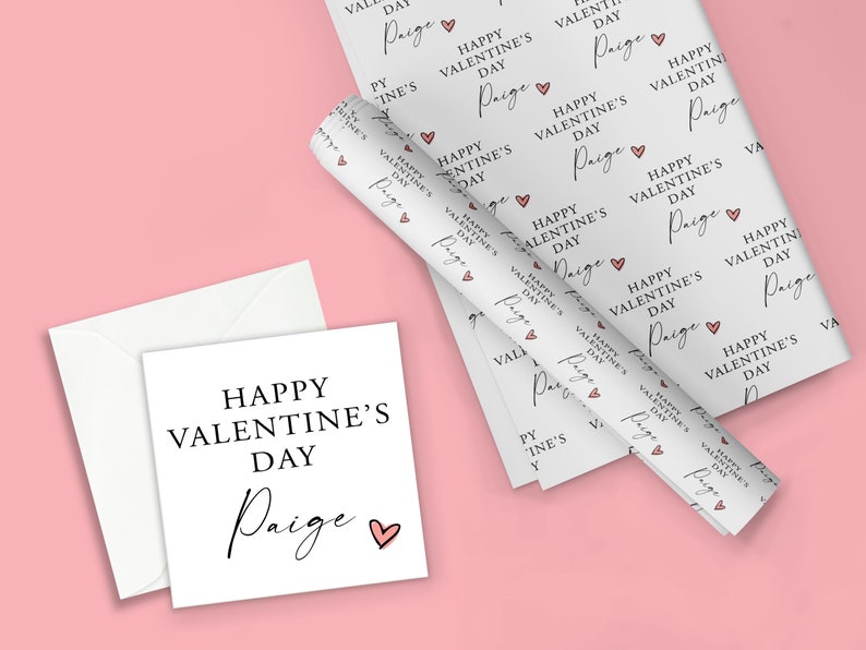 May include: White gift wrap with a repeating pattern of pink hearts and the text "Happy Valentine's Day Paige". A white card with the same text is also shown.