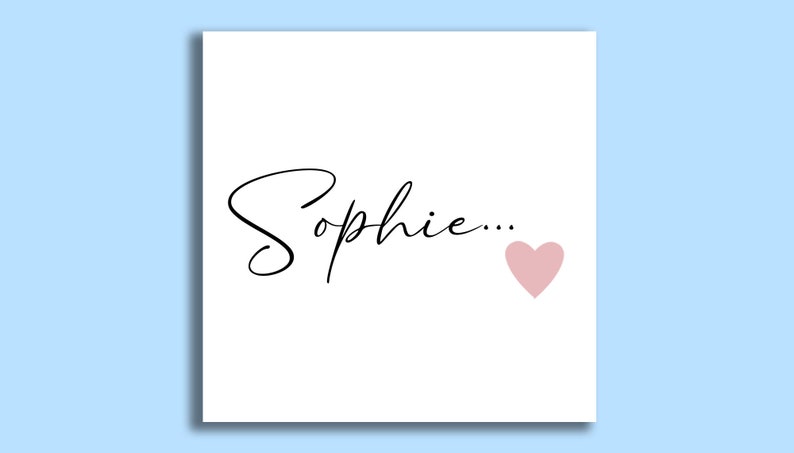 Pu&ograve; includere: Un biglietto bianco con il nome "Sophie..." scritto in corsivo nero e un cuore rosa.