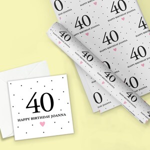 May include: White wrapping paper with a black polka dot pattern and the text "Happy Birthday Joanna" and the number "40" repeated. A pink heart is also included in the design.