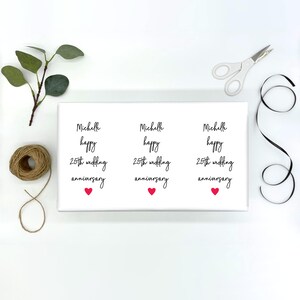 May include: Three white gift tags with black text that reads "Michelle happy 25th wedding anniversary" with a small red heart at the bottom of each tag.