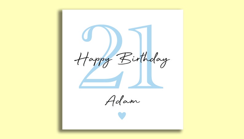 May include: A white birthday card with a light blue "21" and the words "Happy Birthday Adam" in black script. A small blue heart is at the bottom. The card is on a yellow background.