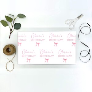 May include: White wrapping paper with a repeating pattern of pink bows and the text "Olivia's Birthday".