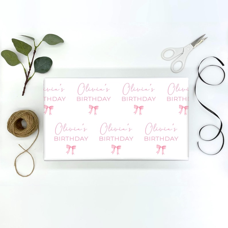 May include: White wrapping paper with a repeating pattern of pink bows and the text "Olivia's Birthday".