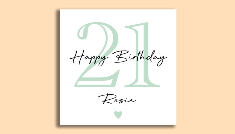 May include: A white birthday card with the number 21 in a soft green color. The words "Happy Birthday" and the name "Rosie" are written in black script. A small green heart is at the bottom.