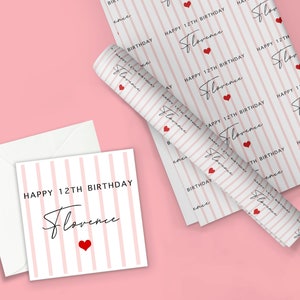 May include: A pink and white striped gift wrapping paper with the text "Happy 12th Birthday Florence" repeated on the paper. A red heart is included in the design. The paper is rolled up and a white card with the same text and a red heart is next to it.