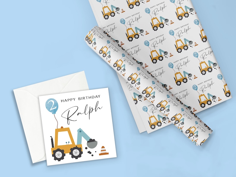 K&ouml;nnte beinhalten: Eine wei&szlig;e Karte mit einem gelben Baufahrzeug und einem blauen Ballon mit der Zahl 2. Der Text "HAPPY BIRTHDAY Ralph" steht auf der Karte.