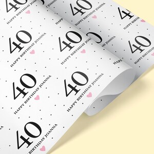 May include: White wrapping paper with a repeating pattern of black numbers "40" and the text "Happy Birthday Joanna" with a pink heart.