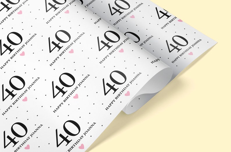 May include: White wrapping paper with a repeating pattern of black numbers "40" and the text "Happy Birthday Joanna" with a pink heart.