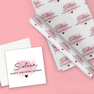 May include: Pink and white wrapping paper with a watercolor design and the text "Sixteen Happy Birthday Sophie". The paper is rolled up and there is a white card with the same design and text.