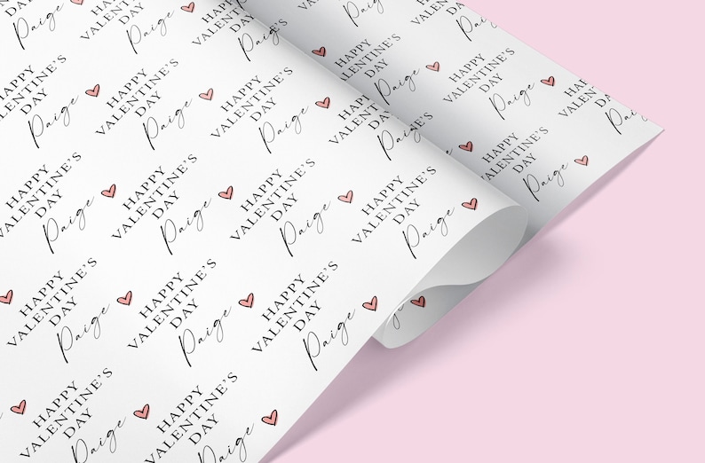 May include: White wrapping paper with a repeating pattern of pink hearts and the text "Happy Valentine's Day Paige".