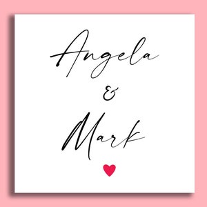 K&ouml;nnte beinhalten: Eine wei&szlig;e Karte mit schwarzer Kalligraphie, auf der "Angela & Mark" steht, darunter ein kleines rotes Herz.
