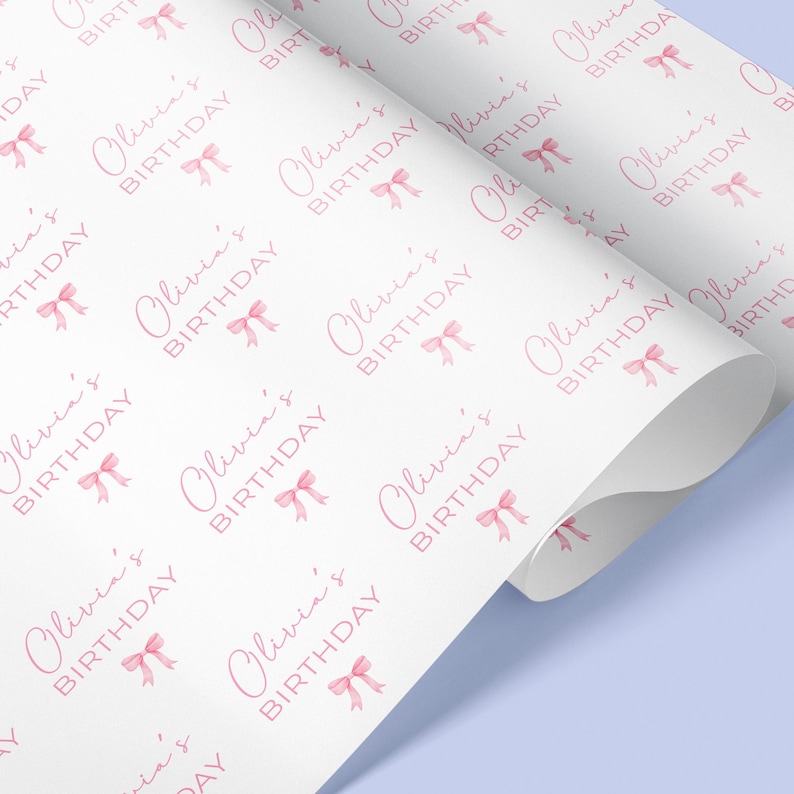May include: White wrapping paper with a repeating pattern of pink bows and the text "Olivia's Birthday".