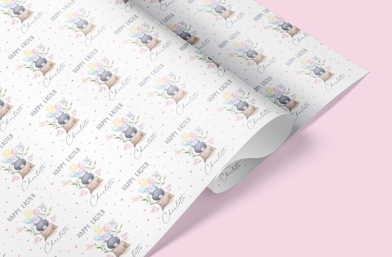 May include: White wrapping paper with a repeating pattern of a bunny holding balloons and flowers. The text "Happy Easter" and the name "Charlotte" are repeated throughout the pattern.