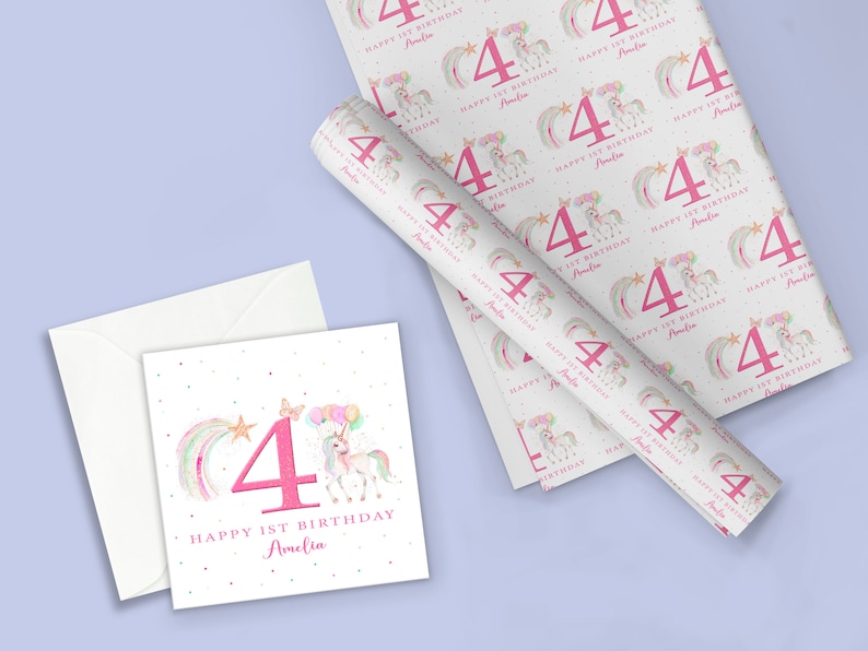 May include: A white card with a pink number four, a rainbow, a star, and a unicorn with balloons. The text reads "Happy 1st Birthday Amelia". The card is on a white envelope. A roll of wrapping paper with a repeating pattern of pink number fours, rainbows, stars, and unicorns with balloons. The text on the wrapping paper reads "Happy 1st Birthday Amelia".