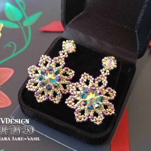 May include: A pair of gold and purple beaded earrings with iridescent crystal accents. The earrings are in a black velvet box.