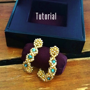 May include: A pair of gold hoop earrings with turquoise blue gemstones. The earrings are on a burgundy velvet surface. The text "Tutorial" is visible in the background.