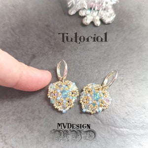Pode incluir: Um par de brincos de prata com detalhes de contas azuis e douradas. Os brincos têm o formato de uma flor e um design delicado. Os brincos estão pendurados em um gancho de prata.