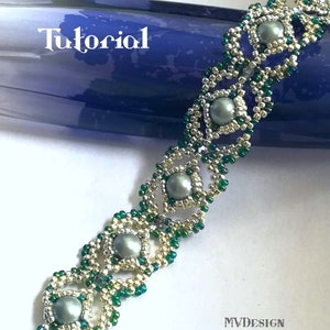 May include: A beaded bracelet with a silver and green color scheme. The bracelet features a repeating pattern of small beads and larger, round, gray beads. The bracelet is made with seed beads and has a clasp closure.
