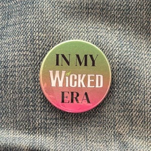 May include: A green, pink and white button with the text "In My Wicked Era" in black.