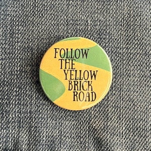 May include: A yellow and green button with the text "FOLLOW THE YELLOW BRICK ROAD" in black.