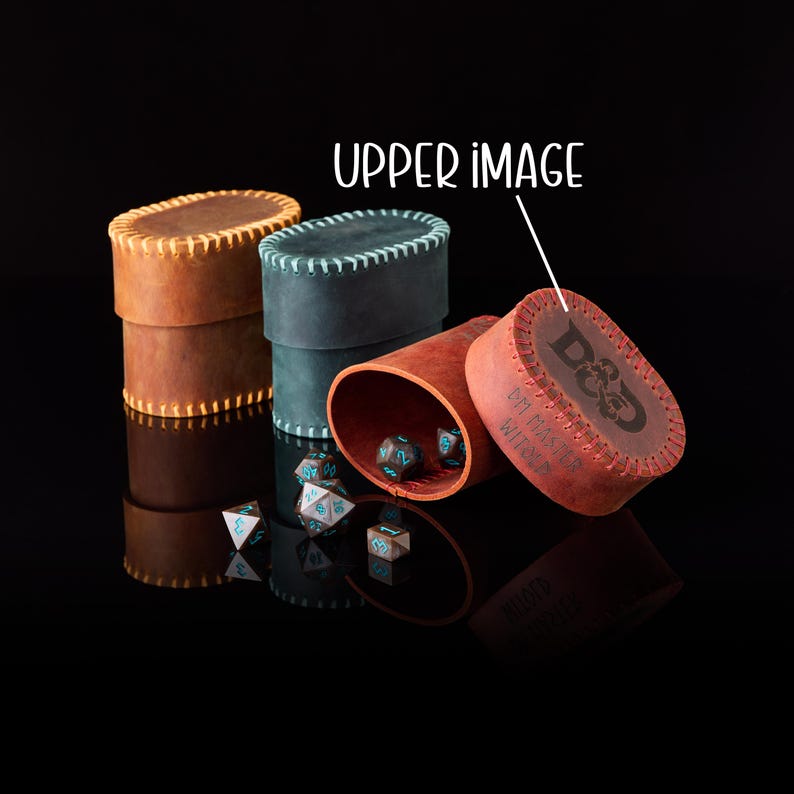 May include: Three oval leather containers with stitched edges in tan, dark blue, and reddish-brown. The reddish-brown lid features the text D&D and DM MASTER. Several multi-sided dice with blue numbers are scattered around the containers.