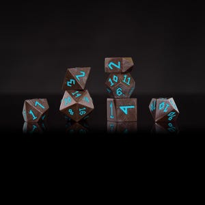 Pu&ograve; includere: Un set di sette dadi poliedrici marroni con numeri blu turchese. I dadi sono disposti su una superficie nera, ognuno dei quali mostra una faccia diversa. Questi dadi sono per i giochi di ruolo.