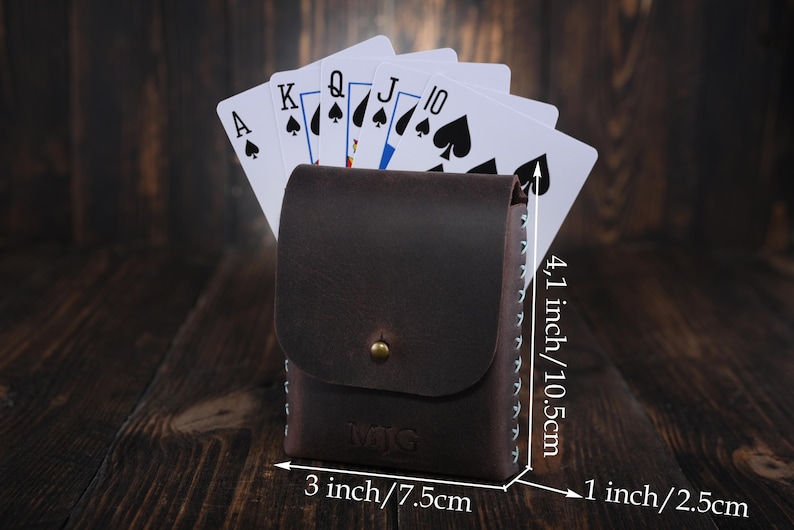 Puede incluir: Un porta tarjetas de cuero marr&oacute;n con detalles de costura. El porta tarjetas mide 10,5 cm de alto, 7,5 cm de ancho y 2,5 cm de profundidad. El porta tarjetas se muestra con cartas de juego en su interior.