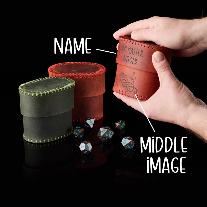 May include: Two cylindrical leather dice cases, one olive green and one reddish-brown, featuring visible stitched edges. The reddish-brown case is engraved with the text DM MASTER WITOLD and a knotwork design. Several polyhedral dice are scattered nearby.