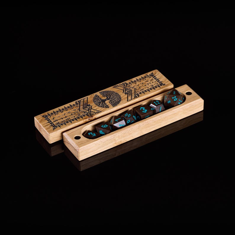 Pu&ograve; includere: Set di dadi in legno con un disegno di albero intagliato sul coperchio. Il set include sette dadi poliedrici con numerazione turchese, riposti in una scatola di legno abbinata. La scatola &egrave; aperta, rivelando i dadi. Lo sfondo &egrave; nero.