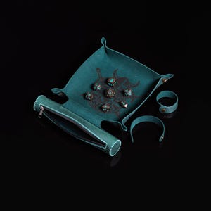 Pu&ograve; includere: Un set da gioco di dadi in pelle verde acqua con vassoio, sacchetto e due braccialetti. Il vassoio presenta una grafica marrone scuro e contiene diversi dadi a pi&ugrave; facce. Il sacchetto per dadi &egrave; cilindrico con cerniera.