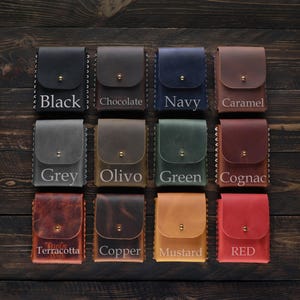Puede incluir: Doce porta tarjetas de cuero en varios colores, incluyendo negro, gris, oliva, verde, co&ntilde;ac, terracota, cobre, mostaza y rojo. Cada porta tarjetas tiene un borde cosido y un peque&ntilde;o bot&oacute;n de metal.