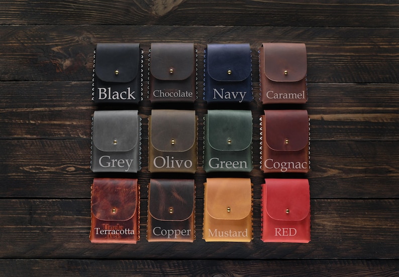 Puede incluir: Doce porta tarjetas de cuero en varios colores, incluyendo negro, gris, oliva, verde, co&ntilde;ac, terracota, cobre, mostaza y rojo. Cada porta tarjetas tiene un borde cosido y un peque&ntilde;o bot&oacute;n de metal.