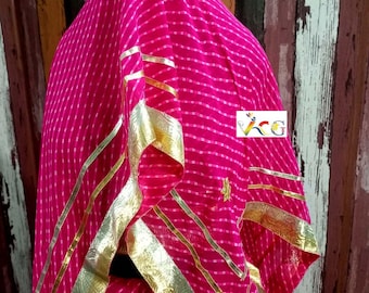 May include: A vibrant pink fabric with white stripes and gold trim. The fabric is draped, showcasing the design and texture. The gold trim adds a touch of elegance to the overall look. The fabric appears to be part of a garment.